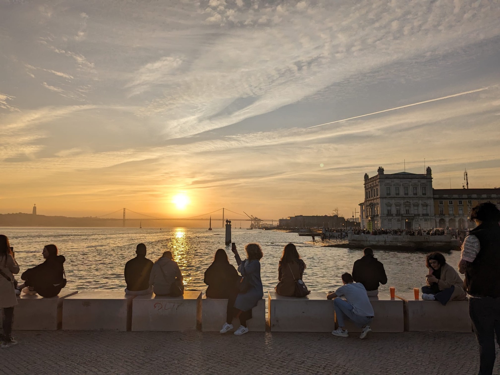 Sunset over the Tagus river at Praça do Comércio in Lisbon, with the 25 de Abril bridge in the distance